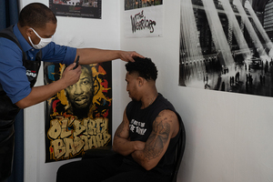 Darren Morgan (left) takes photos of Ronyell Gerton after finishing a haircut. Darren Morgan and Rolando Cabral run their barbershop Royal Allure from a house on Euclid Avenue.