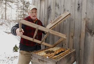 Carlic disassembles one of his beehives to feed his bees. During the winter, the bees cluster together around the queen bee, keeping warm by rotating from the inside to the outside. Temperatures inside the beehive range from 46 to 80 degrees.