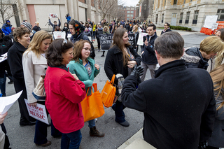 Admitted students and parents are greeted by university officials at a Carrier Dome entrance as student protesters scream chants and hand out flyers.